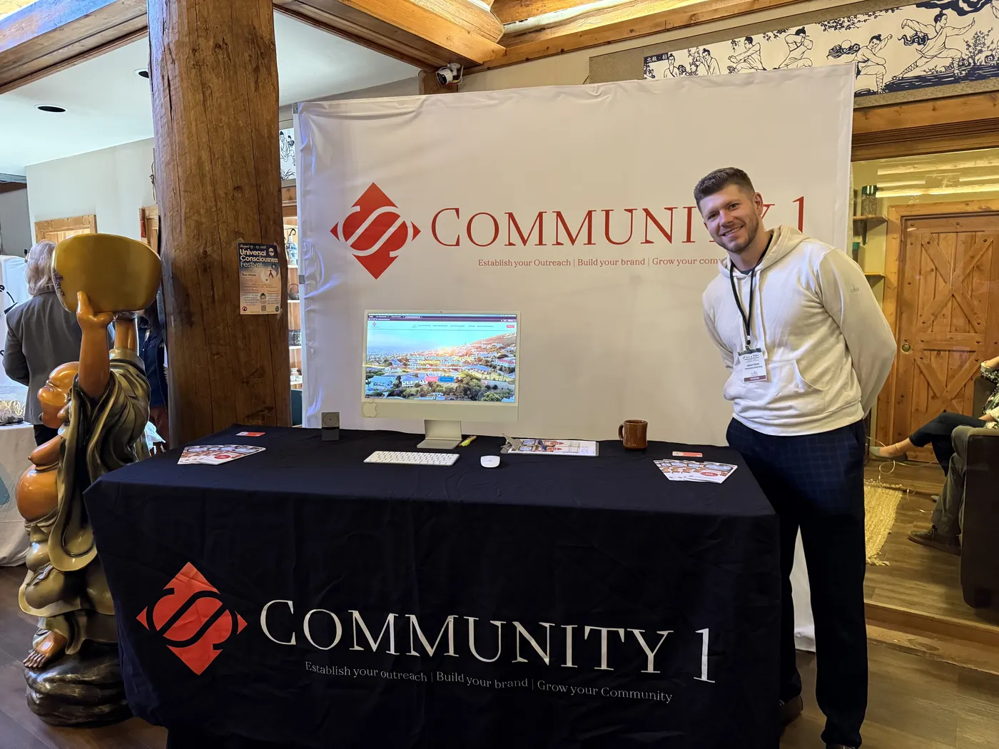 Jason Clark standing beside the Community 1 banner and booth at CoAND 2025